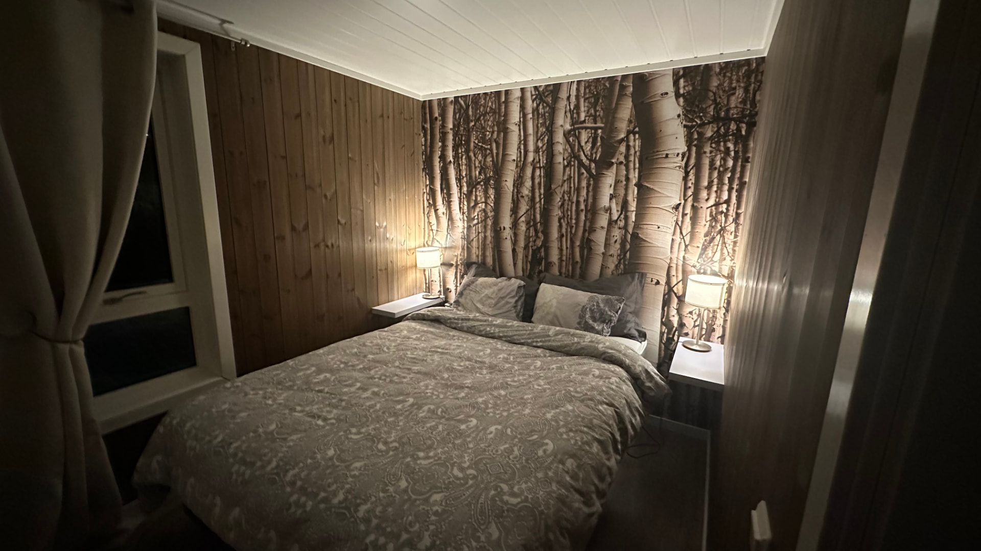 Schlafzimmer mit Holzvertäfelung und Birkenwald-Tapete